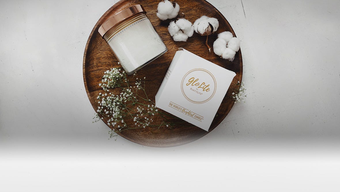 A white GloLite Candle and box displayed next to cotton balls.